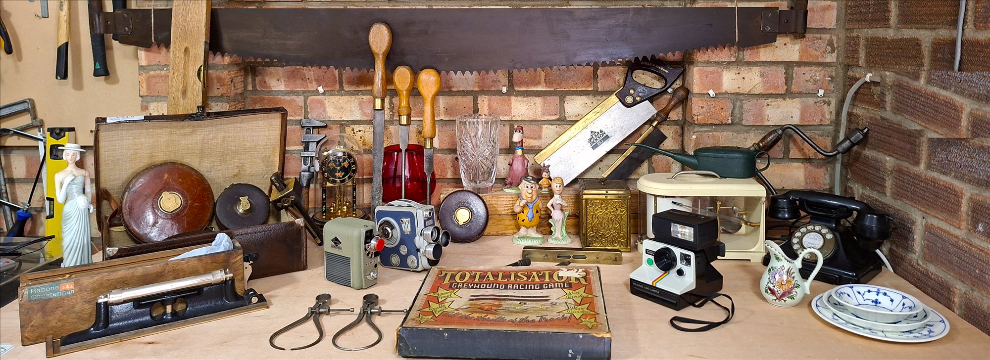 Vintage cameras, tools, ceramics and collectables arranged on a workshop bench.